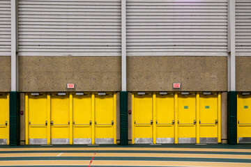 Row of yellow doors inside an indoor arena.