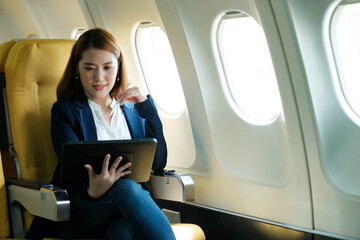 Business woman working on tablet while sitting in airplane.