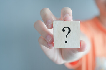 Hand holding question mark symbol on wooden block with copy space. Ask, FAQ, Advice, Support, Problem and solution concept.
