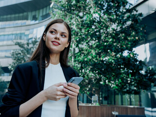 Woman with phone in hand smiles business communication in social networks, lifestyle of the big city