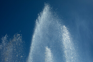 Jets of water against sky. Fountain in city. Details of fountain on street.