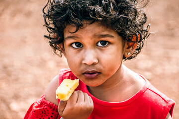 Hungry African child eating food, curiously looking at camera, poor child eating, malnutrition...