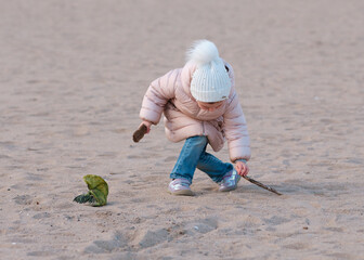 Cute little girl is playing on an empty beach on a cold day