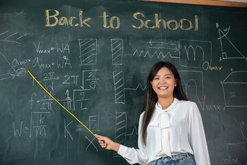 Back to school concept. Happy beautiful young woman standing hold pointer to back board, Asian...