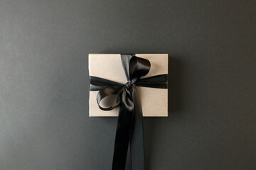 Craft gift box on a dark background, decorated with a textured bow, creating a romantic luxury atmosphere. For birthday, anniversary presents, gift post cards, banner, flyer, invitation, voucher