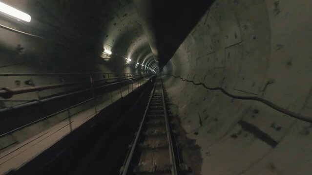 Metro subway with dark tunnel and a train moving fast. Tube lines in tunnel.
