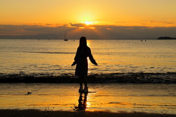 夕暮れの波打ち際でポーズを取る女の子