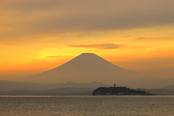 Fototapeta na wymiar 夕焼けに染まる空に浮かび上がる富士山と江ノ島のシルエット