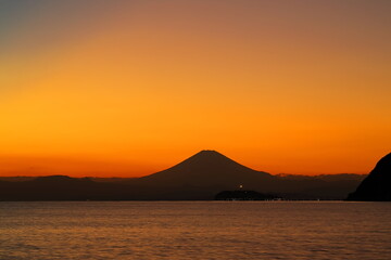Naklejka na ściany i meble 夕焼けに染まる空に浮かび上がる富士山と江ノ島のシルエット