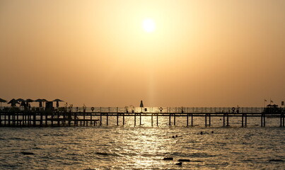 Fototapeta na wymiar Pier on the background of the setting sun. Sea and sun, evening. Pier on the sea, Mediterranean sea