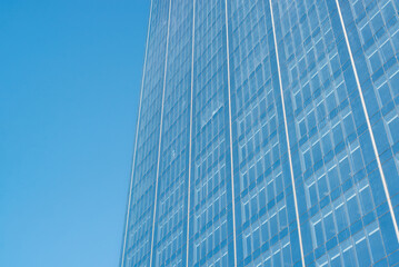 Close-up of a skyscraper, blue glass dirty windows of a modern tall building against a blue clear...