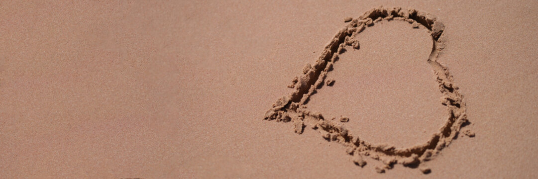 Drawn heart on wet sand on beach