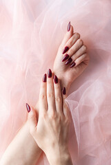 Hands of a young woman with dark red manicure on nails