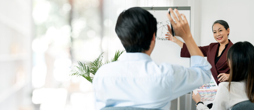 Attractive aged businesswoman presenting or teaching at training seminar room, copy space.