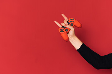 Gamepad in female hand against red background.