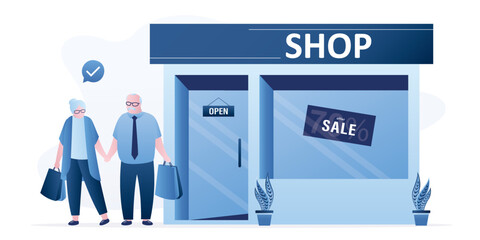 Elderly people leave store with purchases. Couple of grandparents after shopping. Old people holding shopping bags. Showcase of fashion store with discounts.