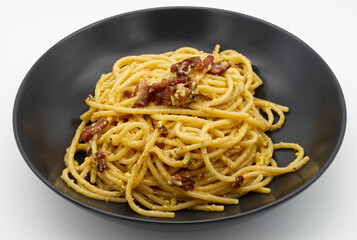 Italian Spaghetti alla Carbonara Pasta in a black dish isolated on white.