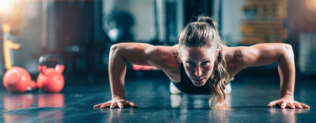 Fototapeten Woman Doing Push-ups in the gym. Strength Training. © Microgen