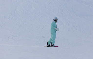Fototapeta na wymiar A woman slides down the mountain on a snowboard in the snow.
