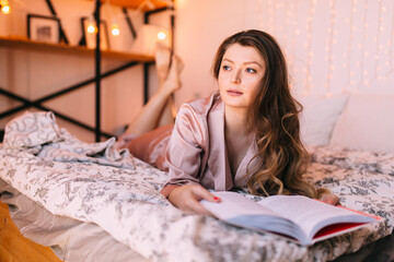 Dreamy and calm young adult woman write in notepad, resting in bedroom