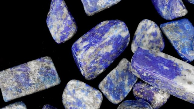 Lapis lazuli heap up jewel stones texture on black background. Moving right seamless loop backdrop.
