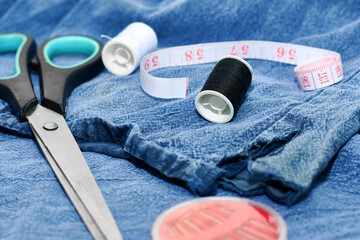 scissors needles measuring tape and thread on the background of torn jeans the concept of reasonable consumption of needlework for small businesses