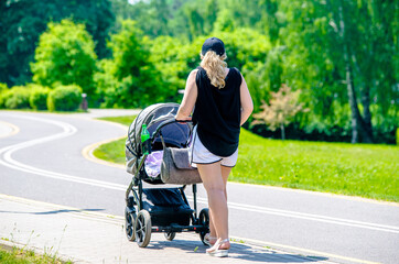 Fototapeta premium Mother wheeling a pram in the Park 