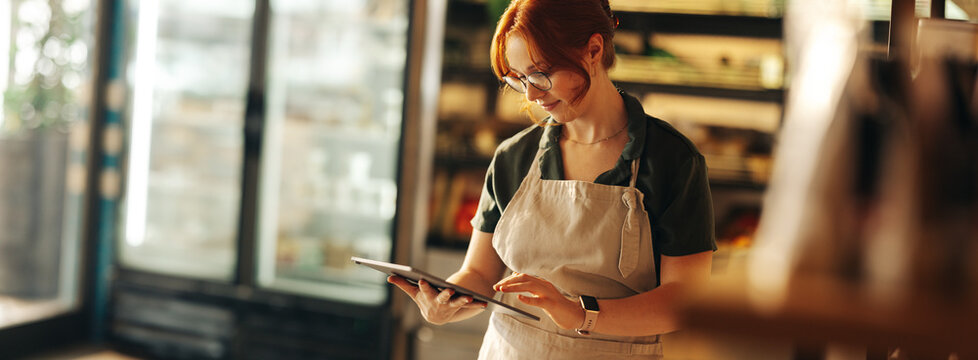 Happy supermarket owner using a digital tablet in her shop