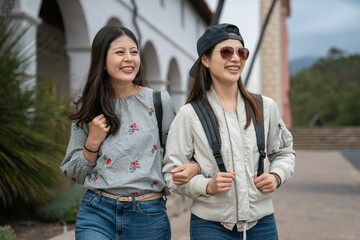 closeup portrait of two asian Taiwanese young women backpackers having fun touring around old mission santa Barbara in usa. they stand arm in arm and look into space with smiling face