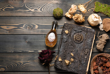 Old magic book and dry natural herbs and remedy bottle on the wooden table flat lay background with...