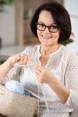 cheerful senior woman is knitting