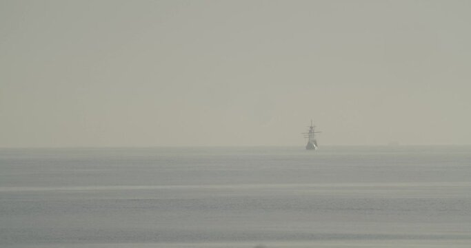 Ferdinand Magellan Nao Victoria carrack boat replica sails in the distance in the mediterranean at sunrise in calm sea in slow motion 60fps