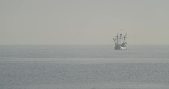 Ferdinand Magellan Nao Victoria carrack boat replica with spanish flag sails in the mediterranean at sunrise in calm sea in slow motion 60fps