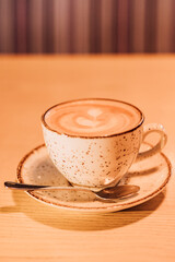 A cup of coffee with milk on a brown background. Hot cappuccino on the table