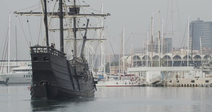 Ferdinand Magellan Nao Victoria carrack boat replica with spanish flag being docked in Valencia with veles e vents in the background in slow motion 60fps