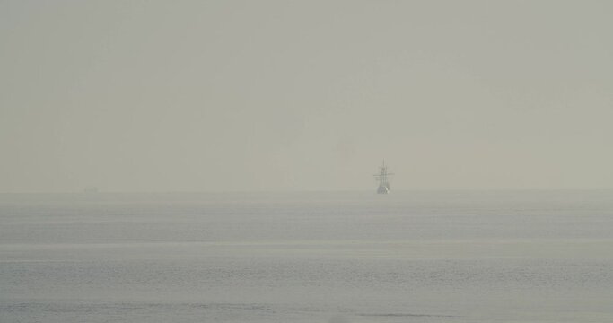 Ferdinand Magellan Nao Victoria carrack boat replica sails in the distance in the mediterranean at sunrise in calm sea in slow motion 60fps