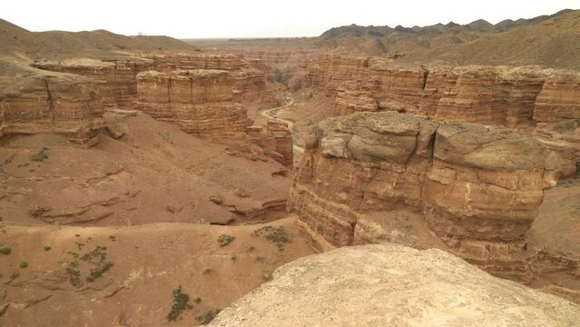 Charyn Canyon red sandstone landscape with car driving in distance, Kazakhstan