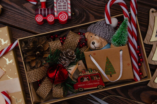 Photo of preparing a gift for Christmas or New Year. Gift box with toys and sweets for family and friends. The atmosphere of holiday and comfort.