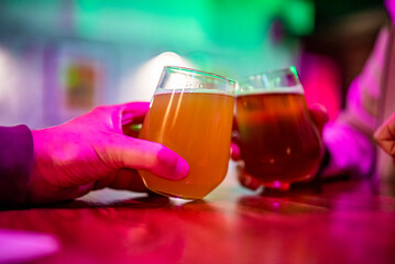 Two friends hands toasting with glasses of craft beer at the pub or bar. taproom