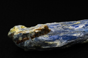 Raw vibrantly blue kyanite crystal stone chunk close up isolated on black surface background