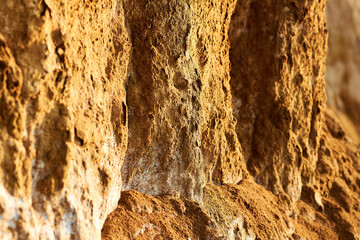 Closeup of crumbling dirt mountainside. Brown textured stone or clay cliff wall. Rough orange mountain environment. Outdoor surface for bouldering and climbing