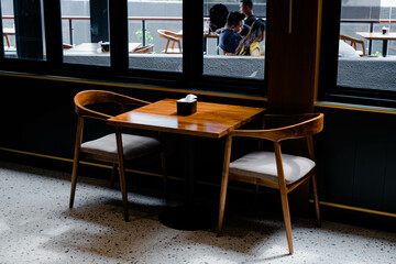 Wooden table and chairs with tissue container in a cafe with dark vibes and terrazzo floor