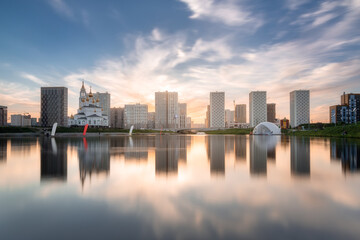 Yekaterinburg city skyline. Buildings of the Academichesky district reflects in mirror surface of the pond at sunset