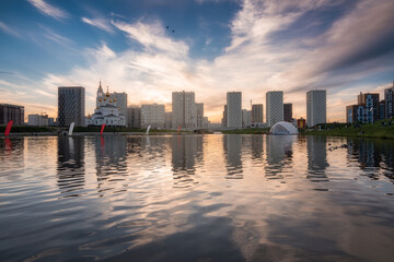 Yekaterinburg city skyline. Buildings of the Academichesky district reflects in water of the pond at beautiful sunset