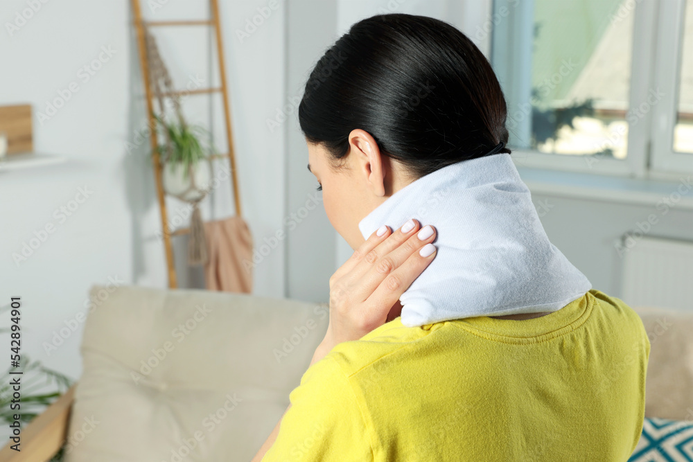 Wall mural woman using heating pad on neck at home