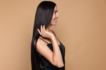 Beautiful young woman with healthy strong hair on beige background