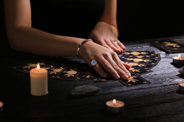 Soothsayer predicting future with tarot cards at table in darkness, closeup