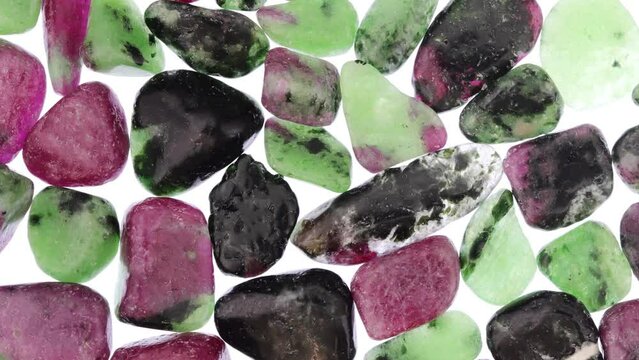 Ruby zoisite jewel stones heap texture on light white isolated background. Moving right seamless loop backdrop.
