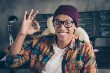 Portrait of cheerful positive hacker guy sit chair hand fingers demonstrate okey symbol workstation...
