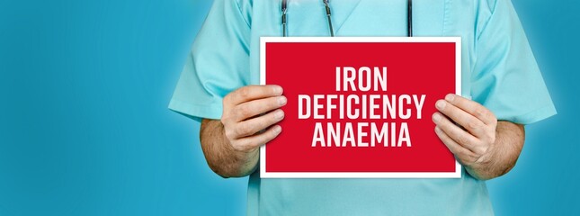 Iron deficiency anaemia. Doctor shows red sign with medical word on it. Blue background.